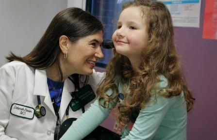 Pediatric provider with patient checking patient's ear