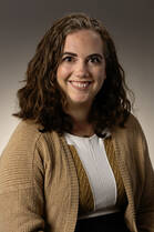 Grace Marrinan, MD, a white woman with dark short hair, poses for a headshot wearing a brown cardigan and white t-shirt.