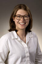 Shea Bellino, MD, a white woman with short brown hair and glasses, poses for a headshot wearing a white button down shirt.
