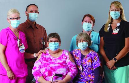 Kathy Tremblay, patient sits smiling, surrounded by her comprehensive inpatient rehabilitation care team