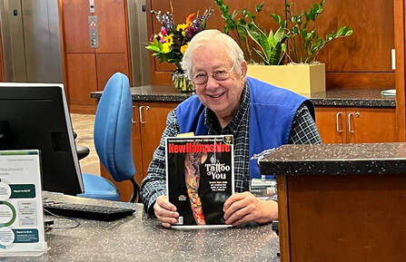 George Scholl holds up a magazine while sitting at a desk