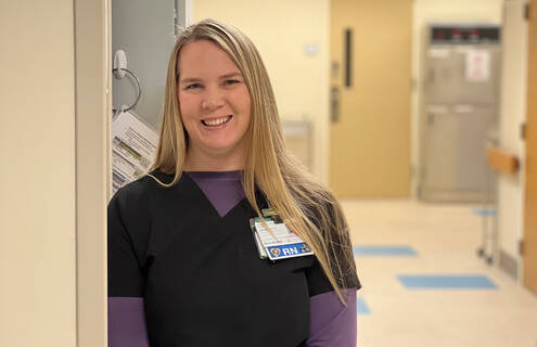 Jen Osborne is a white female nurse with blonde hair leaning next to a doorframe