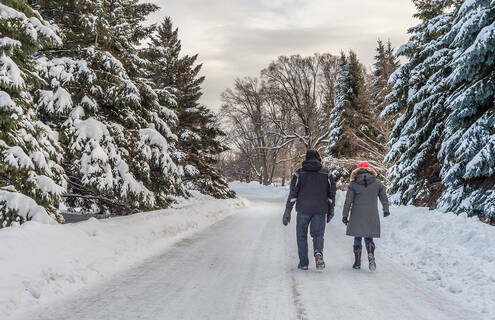 Two people go for a walk on a snowy outdoor trail