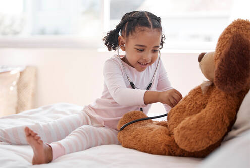 A girl uses a stethoscope on her teddy bear