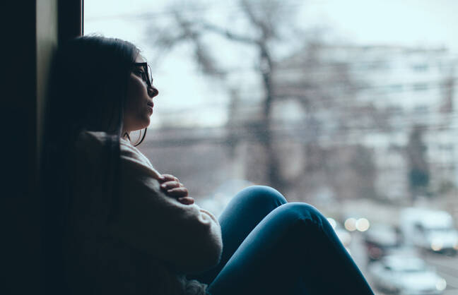 A woman looks out the window at a winter scene