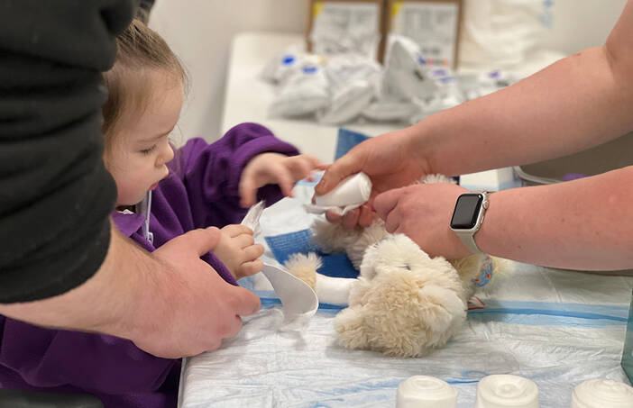 A girl puts a bandage on her teddy bear at the 2025 Teddy Bear Clinic